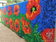 a wall made out of plastic bottles with flowers painted on the outside and inside it