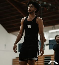 a man standing on top of a basketball court wearing a black and white uniform with the letter d on it