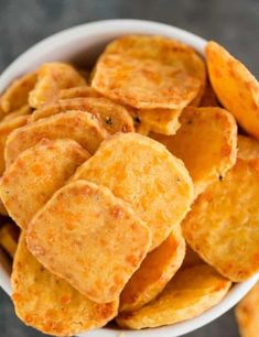 a white bowl filled with potato chips sitting on top of a gray countertop next to other food items