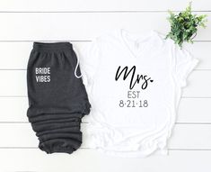 the bride and groom shirts are next to each other on a white background with greenery