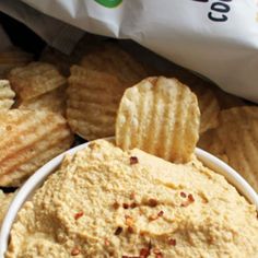 a white bowl filled with chips next to a bag of crackers and potato chips