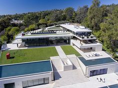 an aerial view of a modern house with swimming pool in the foreground and trees surrounding it