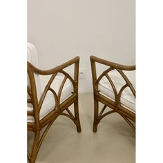 a pair of bamboo chairs sitting next to each other on top of a white floor