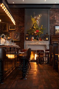 a dimly lit room with bar stools and an antelope painting on the wall