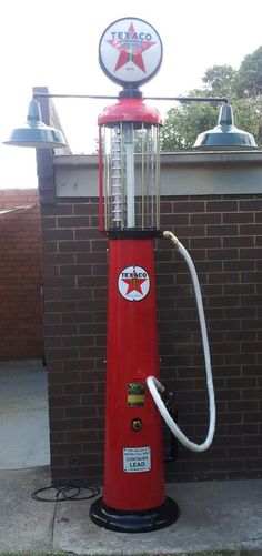 an old fashioned red gas pump sitting on the side of a brick building next to a sign that says texco