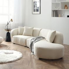 a living room with white furniture and wood flooring, including a large sectional couch