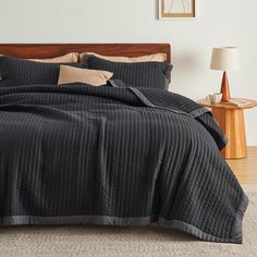 a bed with a black bedspread and two pillows on top of the bed