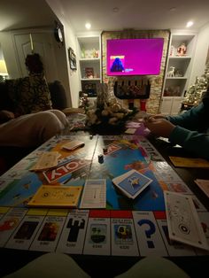 two people sitting at a table in front of a christmas tree with cards on it