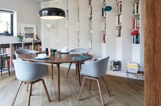 a dining room table surrounded by chairs and bookshelves