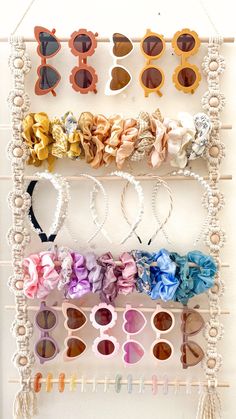 an assortment of sunglasses hanging on a white rack with eye glasses and bows attached to it