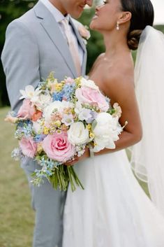 a bride and groom are kissing in front of the camera while holding their wedding bouquet