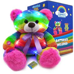 a rainbow colored teddy bear sitting in front of a box with its lights on it