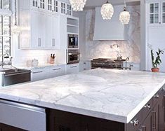 a large kitchen with white cabinets and marble counter tops, along with an island in the middle