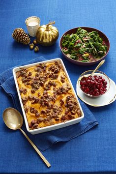 a casserole dish with meat, cheese and vegetables on a blue table cloth