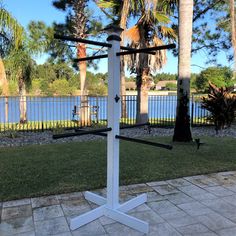 a white pole with three black poles on it in front of some water and palm trees