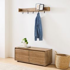 a coat rack with two coats hanging on it next to a basket and potted plant