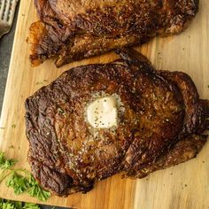 two steaks on a cutting board with parsley