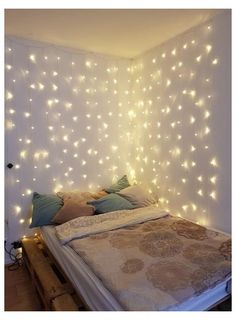 a bed that has some lights on the headboard and pillows in front of it