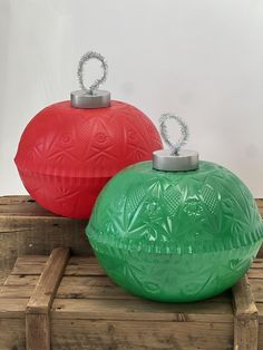 two large red and green vases sitting on top of wooden pallets with metal handles