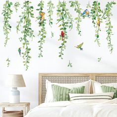 a bedroom with green leaves and birds hanging from the branches on the wall above the bed