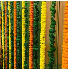 many orange and yellow garlands are hanging on the wall next to eachother