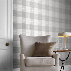 a living room with a chair, lamp and wallpaper on the walls in shades of grey