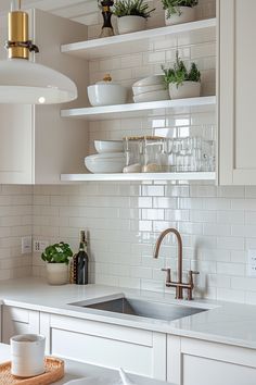 a kitchen with white cabinets and open shelving above the sink is filled with dishes