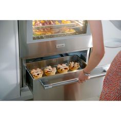 a woman is looking at some food in the oven