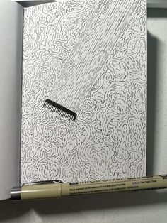 a pencil is laying on top of a drawing book with a black and white design