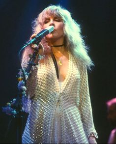 a woman with blonde hair singing into a microphone