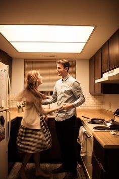 a man and woman standing in a kitchen next to an oven with the lights on