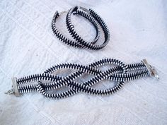 two black and white bracelets laying on top of a white cloth covered tablecloth