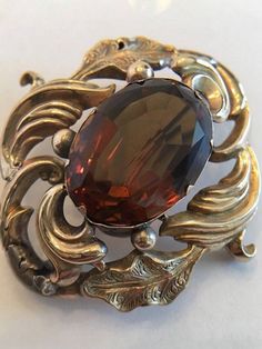 "This is a Very Special Piece. Probably the oldest piece in my inventory. This is an Antique Georgian Brooch with a Large Amber/Brown Topaz in the Center. It is possible it is a Paste Stone. It also has an open hook in the back, at the top, so it can be worn as a pendant if desired. This piece is really well made and in very good condition considering its age. The piece is tested to be 9K Yellow Gold. The large stone is about 1 3/4 \" x 1 3/4\" tall. It weighs 10.7 grams without the stone. I am Vintage Gemstone Brooches, Vintage Gemstone Brooches For Formal Occasions, Ornate Gemstone Brooches For Collectors, Antique Oval Brooches For Evening, Ornate Oval Brooches For Anniversary, Ornate Oval Brooches For Formal Occasions, Ornate Oval Brooch For Formal Occasions, Ornate Oval Anniversary Brooches, Heirloom Oval Brooch For Formal Occasions