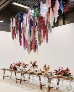 a long table with plates and flowers on it in front of a hanging chandelier