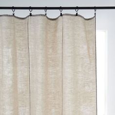 the curtain is hanging in front of an open window with white curtains and black metal rods