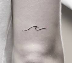 a woman's arm with a small wave tattoo on it