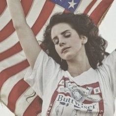 a woman holding an american flag in front of her head and arms with both hands