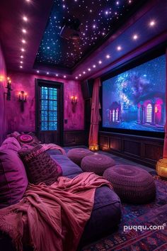 a room with purple walls and lots of pillows on the couches in front of a large screen