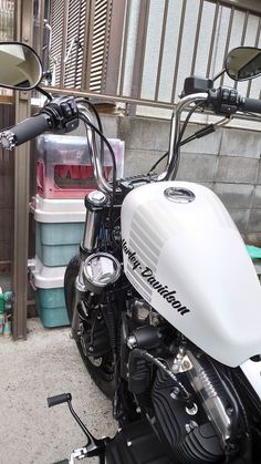 a white motorcycle parked in front of a building next to a pile of plastic containers