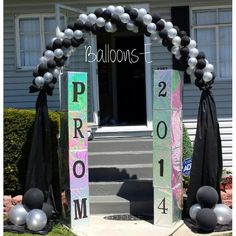 balloons are tied to the front door of a house with black and white decorations on it