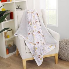 a baby blanket sitting on top of a chair next to a book shelf filled with books