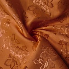 a close up view of a gold colored fabric with flowers and leaves on the side