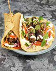 two pita breads with meatballs and veggies on them sitting on a plate