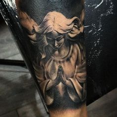 a man's leg with a tattoo on it that has an image of a woman praying