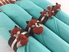 four little foxes are sitting on top of the blue napkins that were wrapped in twine