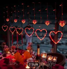 valentine's day table setting with candles, wine glasses and heart shaped lights hanging from the ceiling