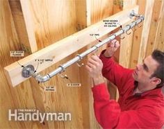 a man is working on metal pipes in the corner of a room with wood paneling