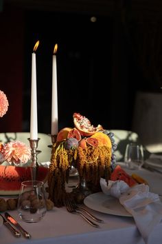 the table is set with watermelon slices and silverware, candles, and flowers