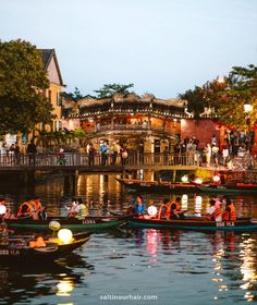 several boats floating on top of a river next to a bridge with people in it