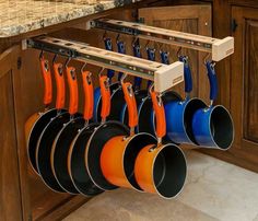 pots and pans are hanging from hooks on the kitchen cabinets in front of an oven